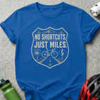 Blue t-shirt with "NO SHORTCUTS. JUST MILES." graphic and bicycle imagery.
