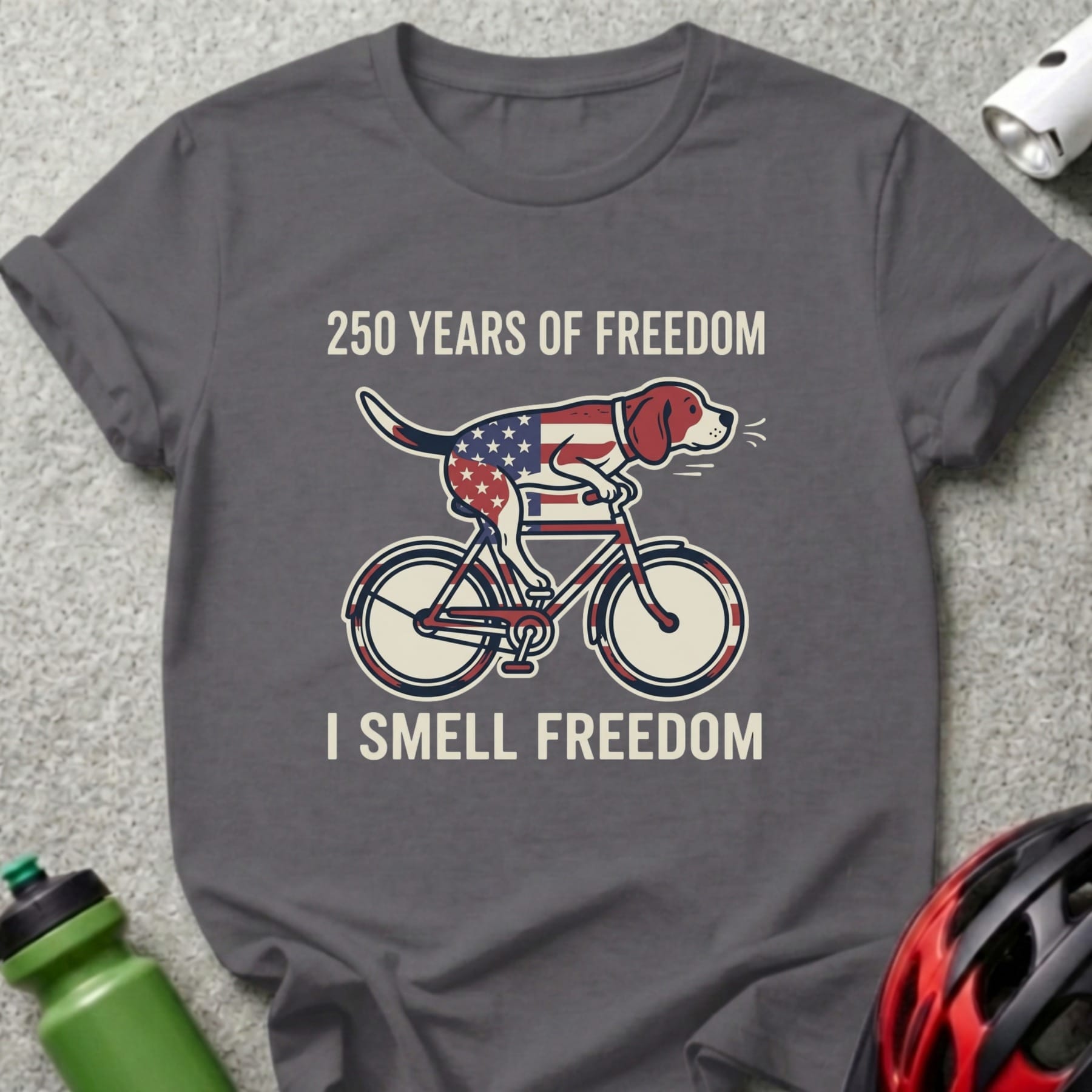 Dog on a bicycle wearing an American flag bandana, "250 Years of Freedom" and "I Smell Freedom" text.
