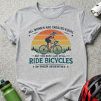 Grey t-shirt with "All women are created equal but the best can still ride bicycles in their seventies" text and cyclist graphic.