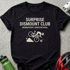 Black t-shirt with "SURPRISE DISMOUNT CLUB MEMBERSHIP: UNINTENTIONAL" text and cycling graphic.