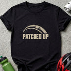 Black t-shirt featuring the beige text "PATCHED UP" under a bicycle tire graphic.
