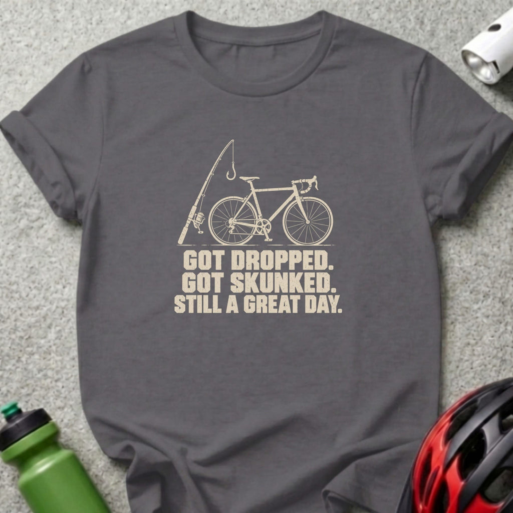 A dark gray t-shirt featuring a white graphic of a bicycle, fishing rod, and text reading GOT DROPPED. GOT SKUNKED. STILL A GREAT DAY.