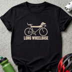 A black short-sleeved t-shirt featuring a beige graphic of a dachshund-shaped bicycle with the text LONG WHEELBASE.