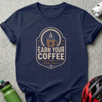 Navy t-shirt with "Earn Your Coffee - Ride First" graphic featuring a bicycle wheel and coffee cup.