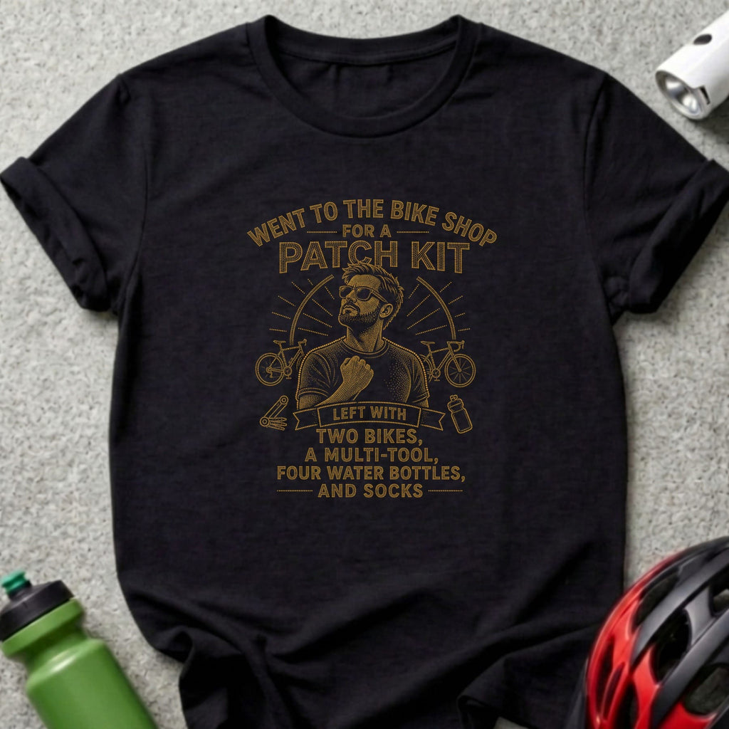 Black t-shirt with gold text reading "Went to the bike shop for a patch kit" and "Left with two bikes, a multi-tool, four water bottles, and socks."