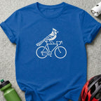 A royal blue crewneck t-shirt featuring a white graphic of a blue jay riding a bicycle.