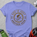 Light purple t-shirt with "Age is just another gear" cyclist graphic.