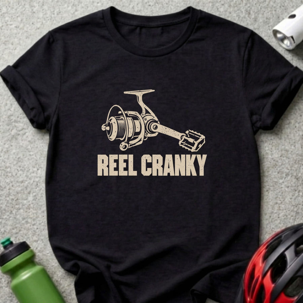 Black t-shirt featuring a graphic of a fishing reel with bicycle pedal handle and text reading REEL CRANKY.