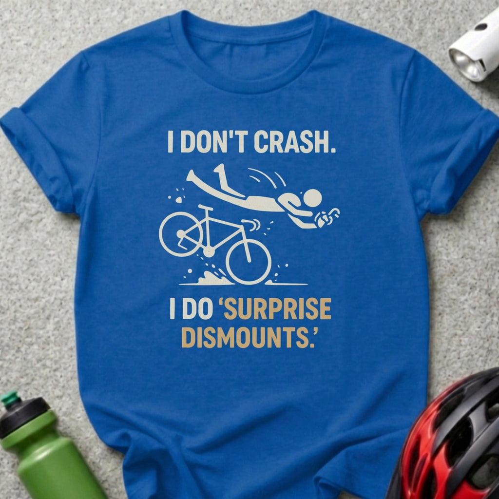 Blue t-shirt with text "I DON'T CRASH. I DO 'SURPRISE DISMOUNTS.'" and a graphic of a cyclist falling.