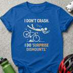 Blue t-shirt with text "I DON'T CRASH. I DO 'SURPRISE DISMOUNTS.'" and a graphic of a cyclist falling.