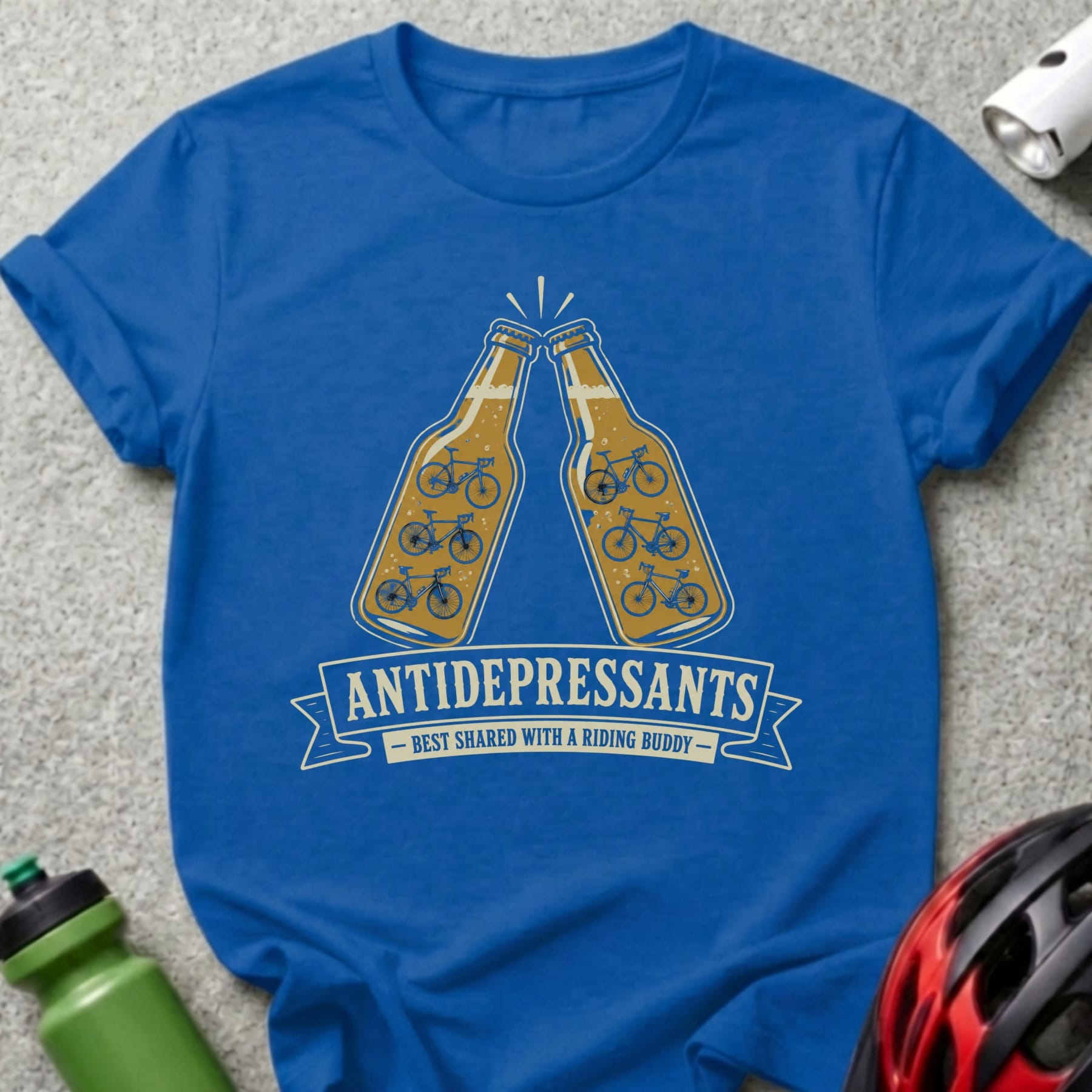 Blue t-shirt with two beer bottles clinking, featuring bicycle silhouettes and "ANTIDEPRESSANTS BEST SHARED WITH A RIDING BUDDY."