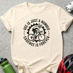 T-shirt with black graphic: cyclist and text "Age is Just a Number, Cadence is Forever".