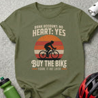 Olive green t-shirt with cyclist graphic and "Bank Account: No Heart: Yes Buy the Bike" text.