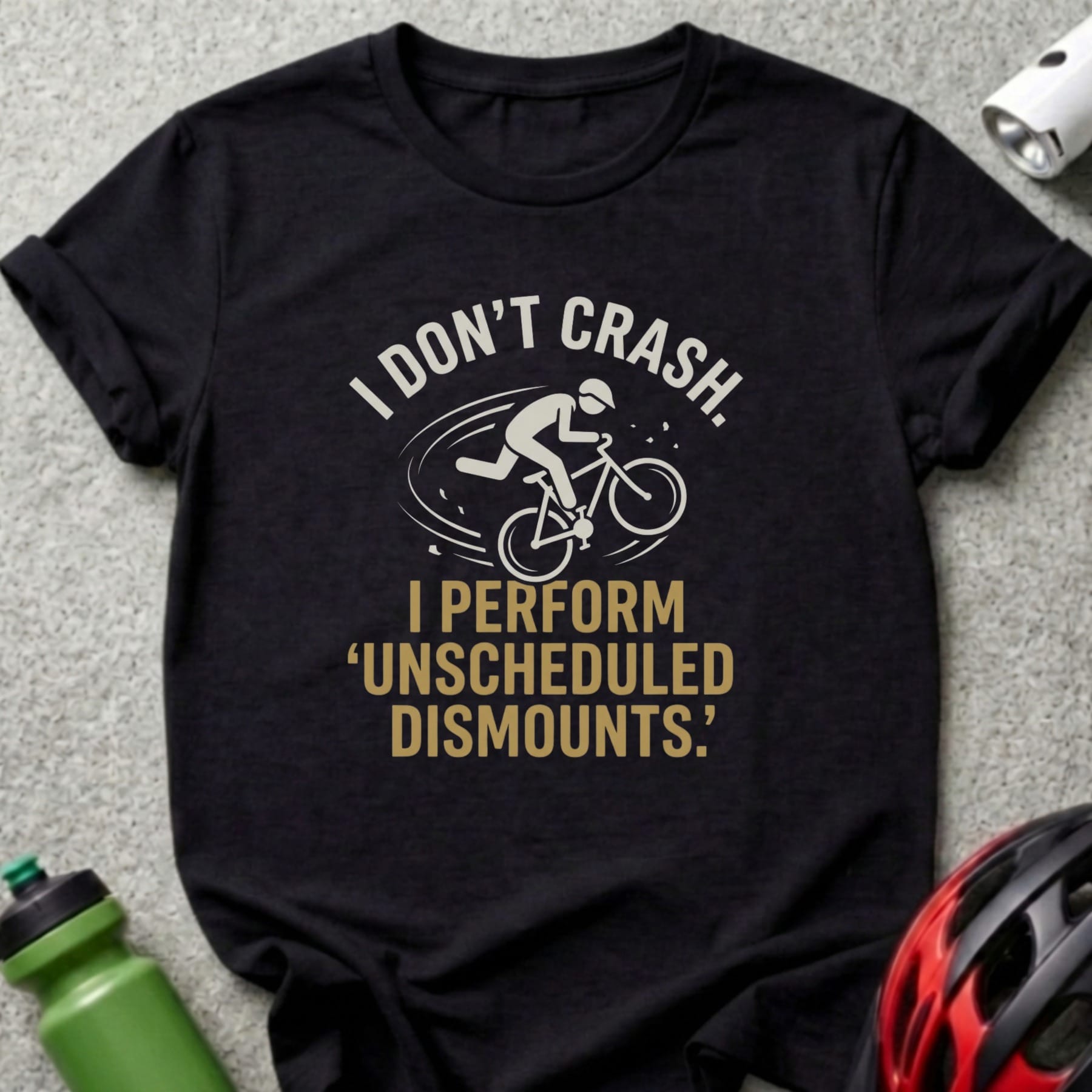 Black t-shirt with white text and cyclist graphic: "I DON'T CRASH. I PERFORM 'UNSCHEDULED DISMOUNTS.'"