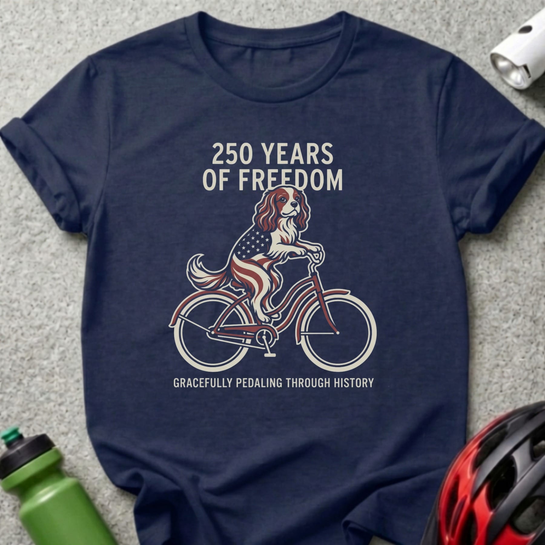 Navy t-shirt with a dog on a bicycle, wearing an American flag cape, and text.