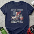 Navy t-shirt with cyclist and dog against American flag, "250 Years of Freedom" text.
