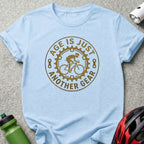 Light blue t-shirt with "Age is just another gear" cycling graphic.