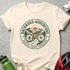 Gravel bike with mountains and sun graphic on cream t-shirt.