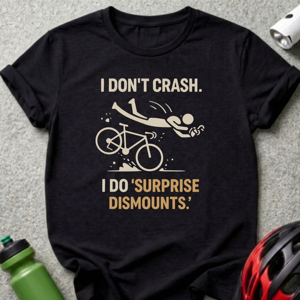 Black t-shirt with "I DON'T CRASH. I DO 'SURPRISE DISMOUNTS.'" text and a falling cyclist graphic.