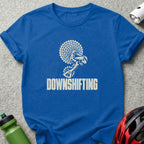 Blue t-shirt featuring a white graphic of bicycle gears and the text DOWNSHIFTING, surrounded by cycling accessories.