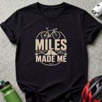 Black t-shirt with "Miles Made Me" text and bicycle graphic.