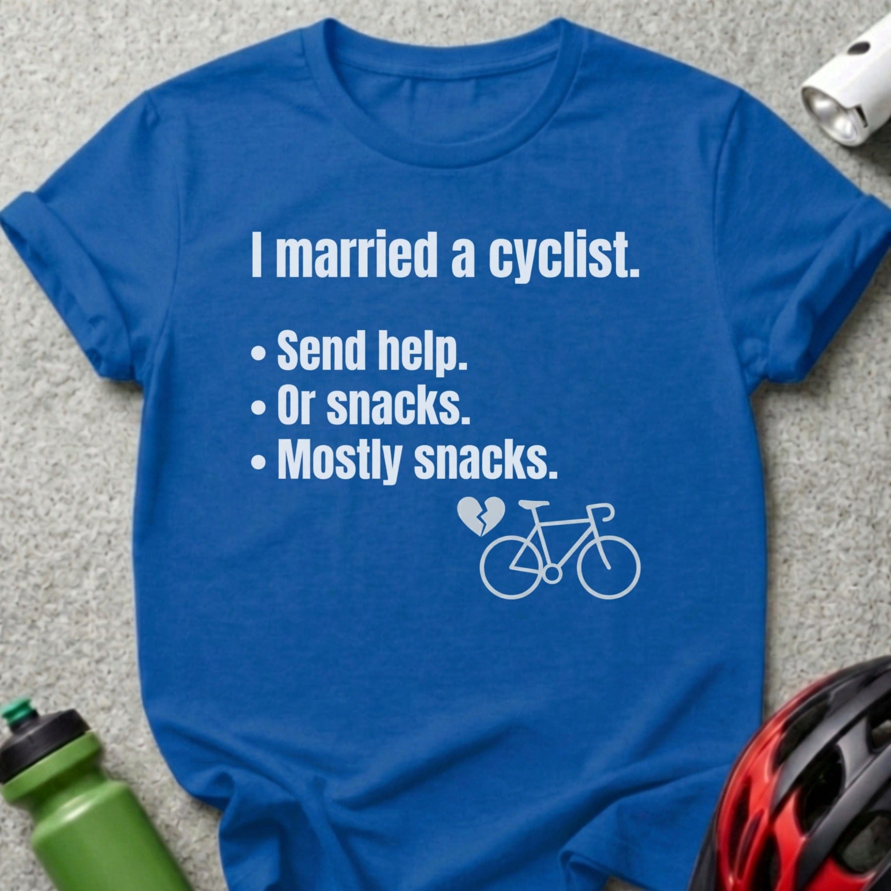 Blue t-shirt with text "I married a cyclist. Send help. Or snacks. Mostly snacks." and bicycle graphic.