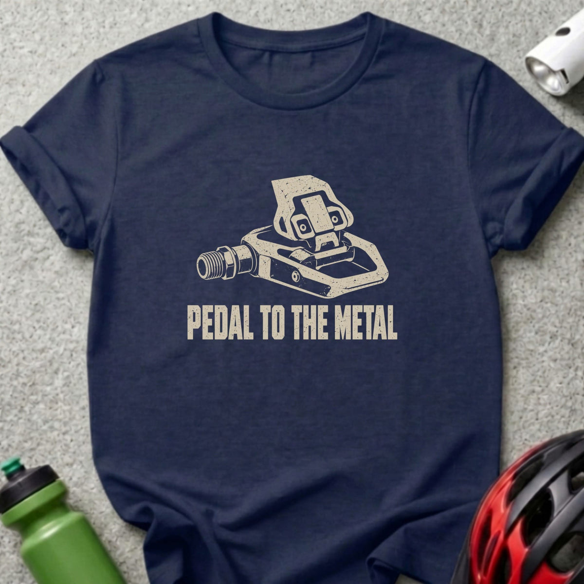 A navy blue t-shirt with a graphic of a bicycle pedal and the text PEDAL TO THE METAL.