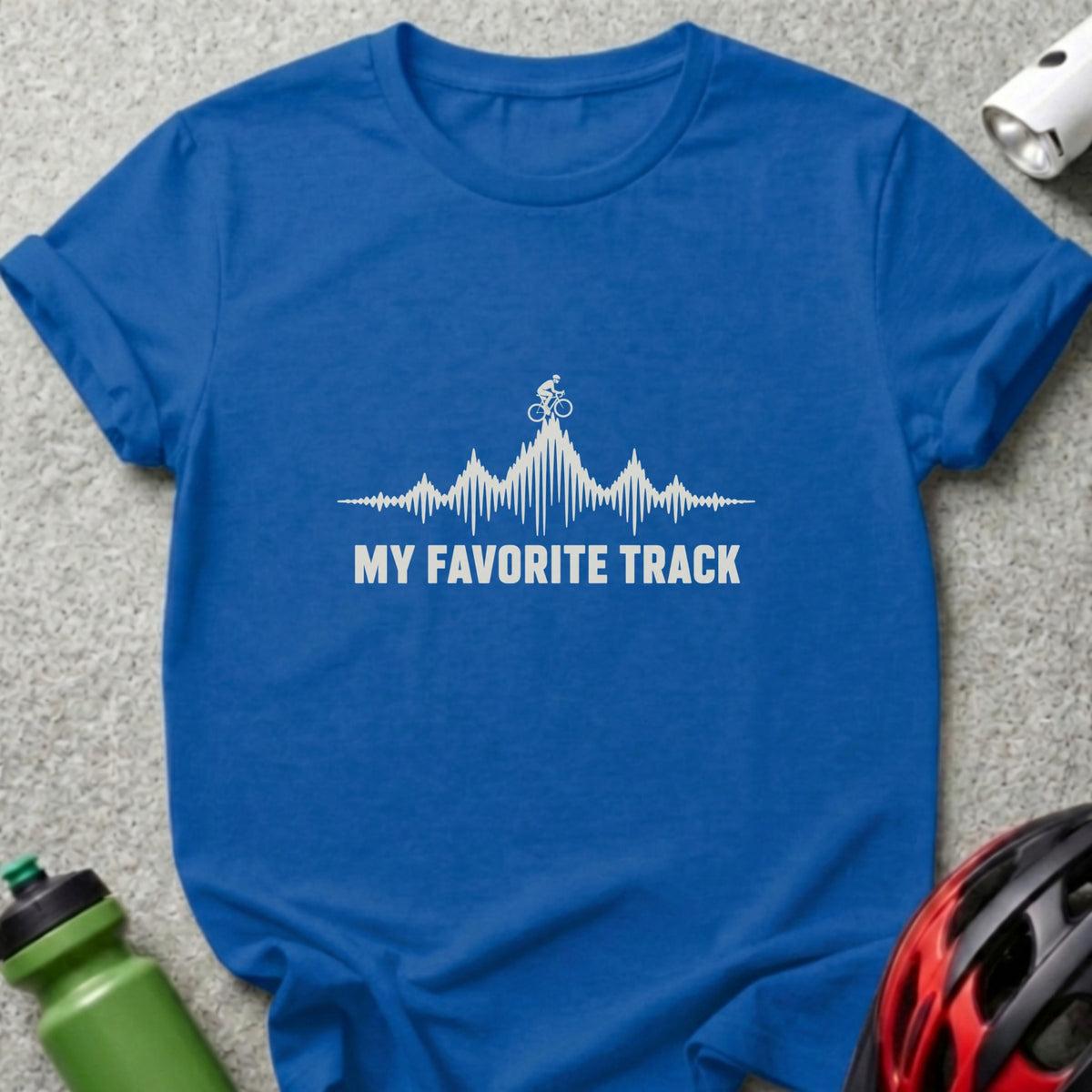 A royal blue crewneck t-shirt featuring a white graphic of a cyclist on a mountain range resembling an audio waveform and the text "MY FAVORITE TRACK".