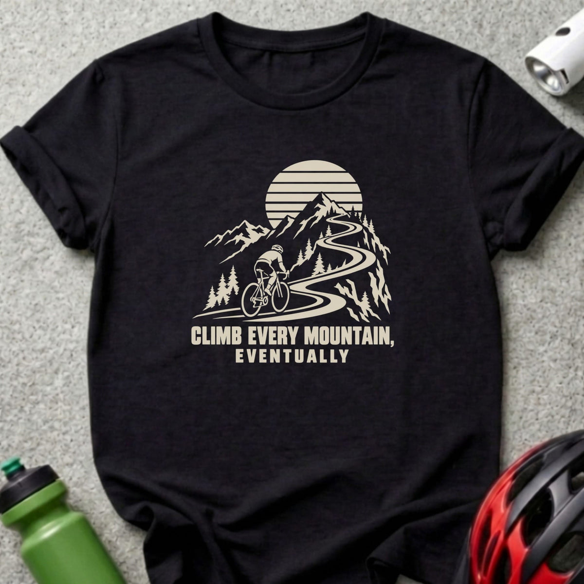 Black t-shirt featuring a graphic of a cyclist on a mountain road with the text Climb Every Mountain Eventually.