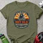 Olive green t-shirt with "Built for Distance Not Old Still Clocking Miles" cyclist graphic.