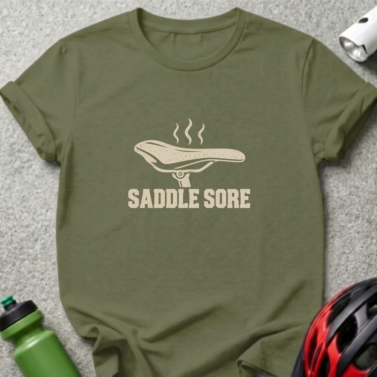 Olive green t-shirt with a bicycle saddle graphic and the text "SADDLE SORE".