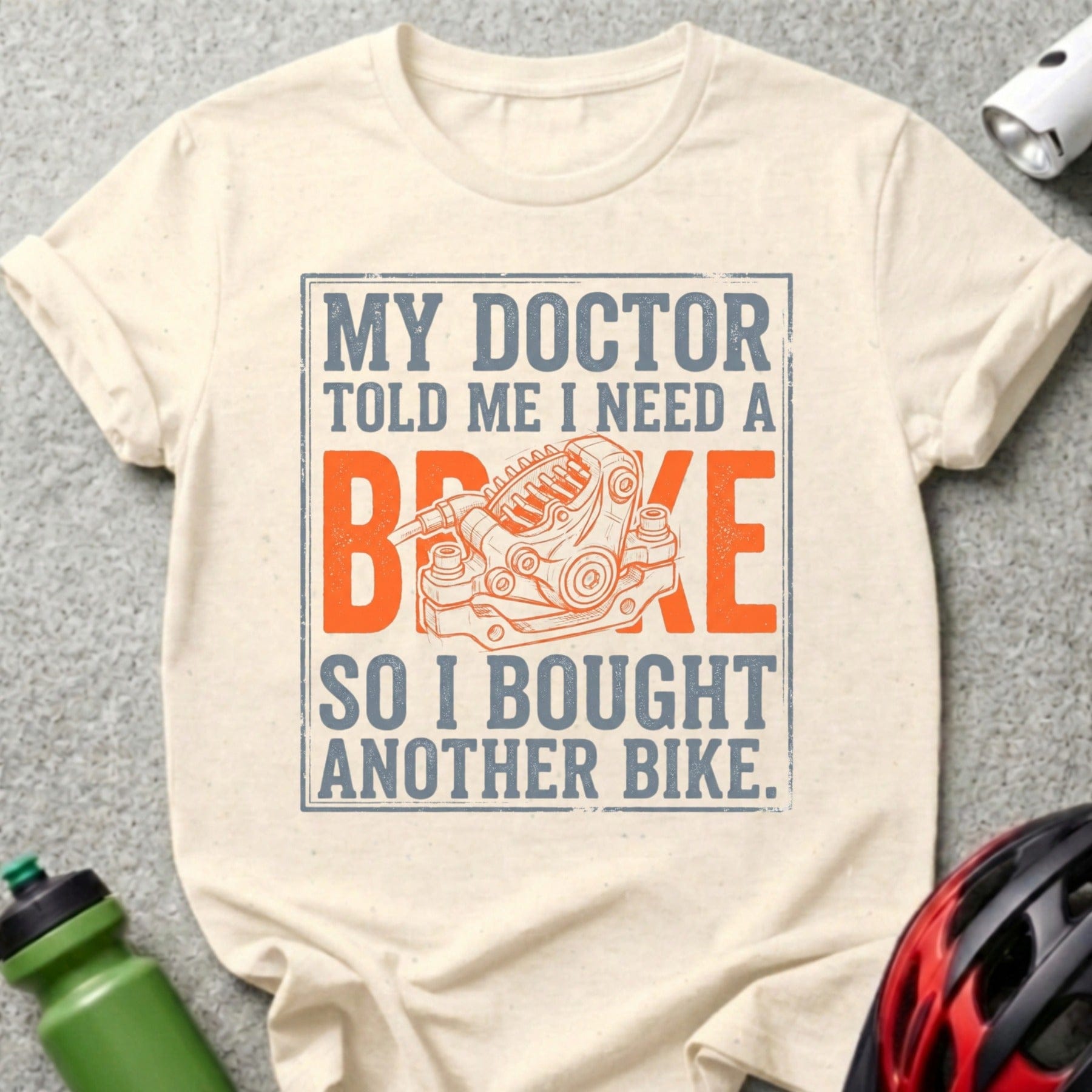 Cream t-shirt with "My doctor told me I need a brake, so I bought another bike" and bike brake graphic.
