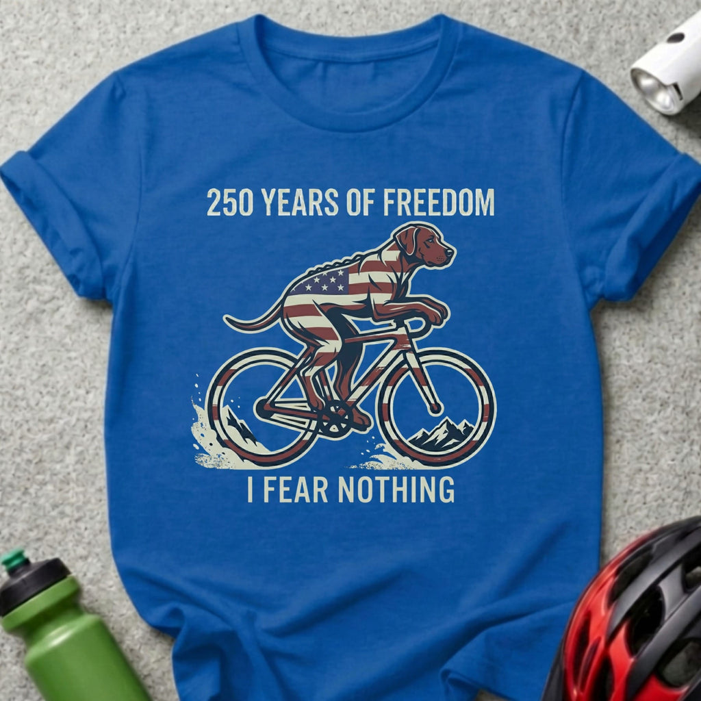 Blue t-shirt with dog wearing USA flag and riding a bike, reads "250 Years of Freedom I Fear Nothing."