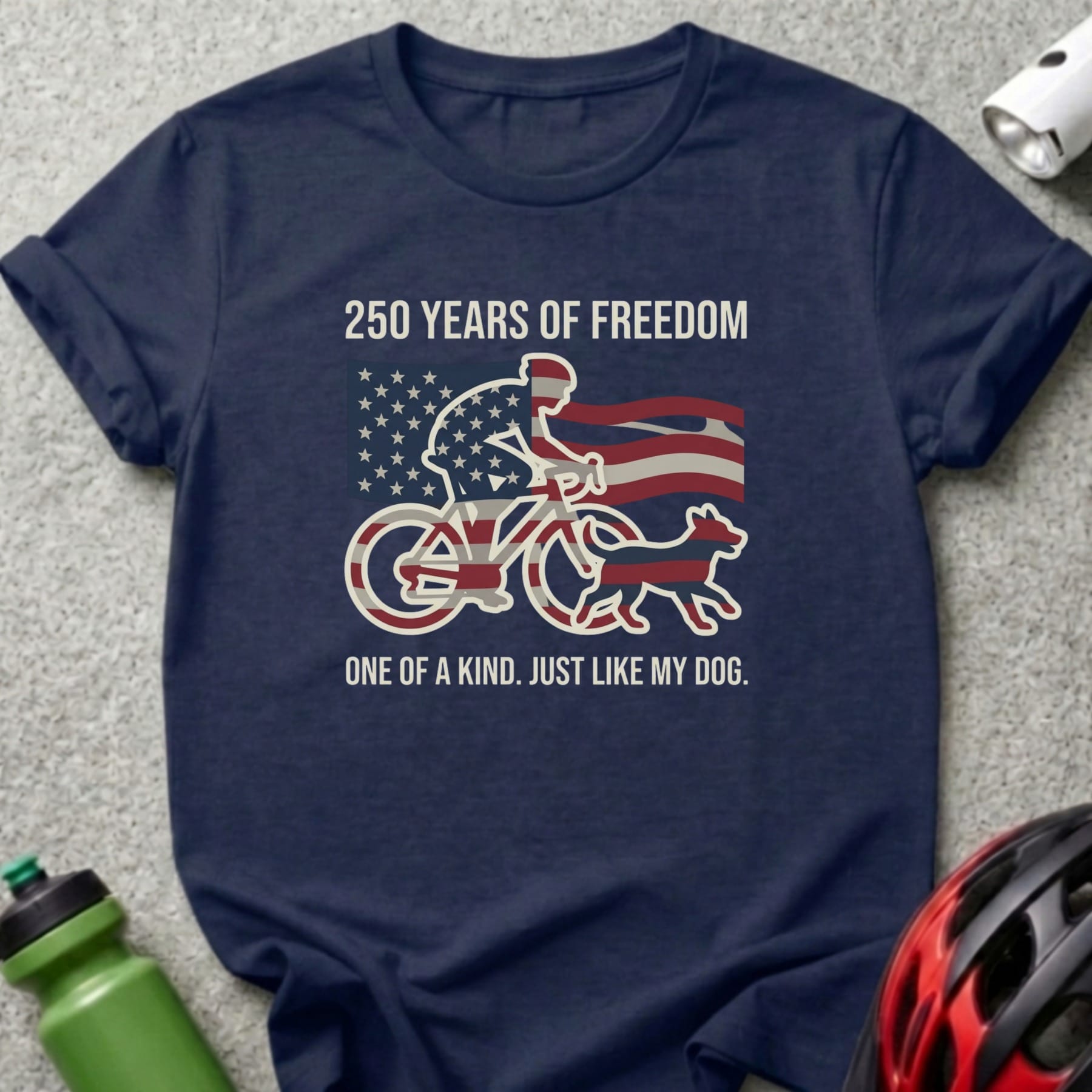 Navy t-shirt with cyclist, dog, American flag, and text "250 YEARS OF FREEDOM ONE OF A KIND. JUST LIKE MY DOG."
