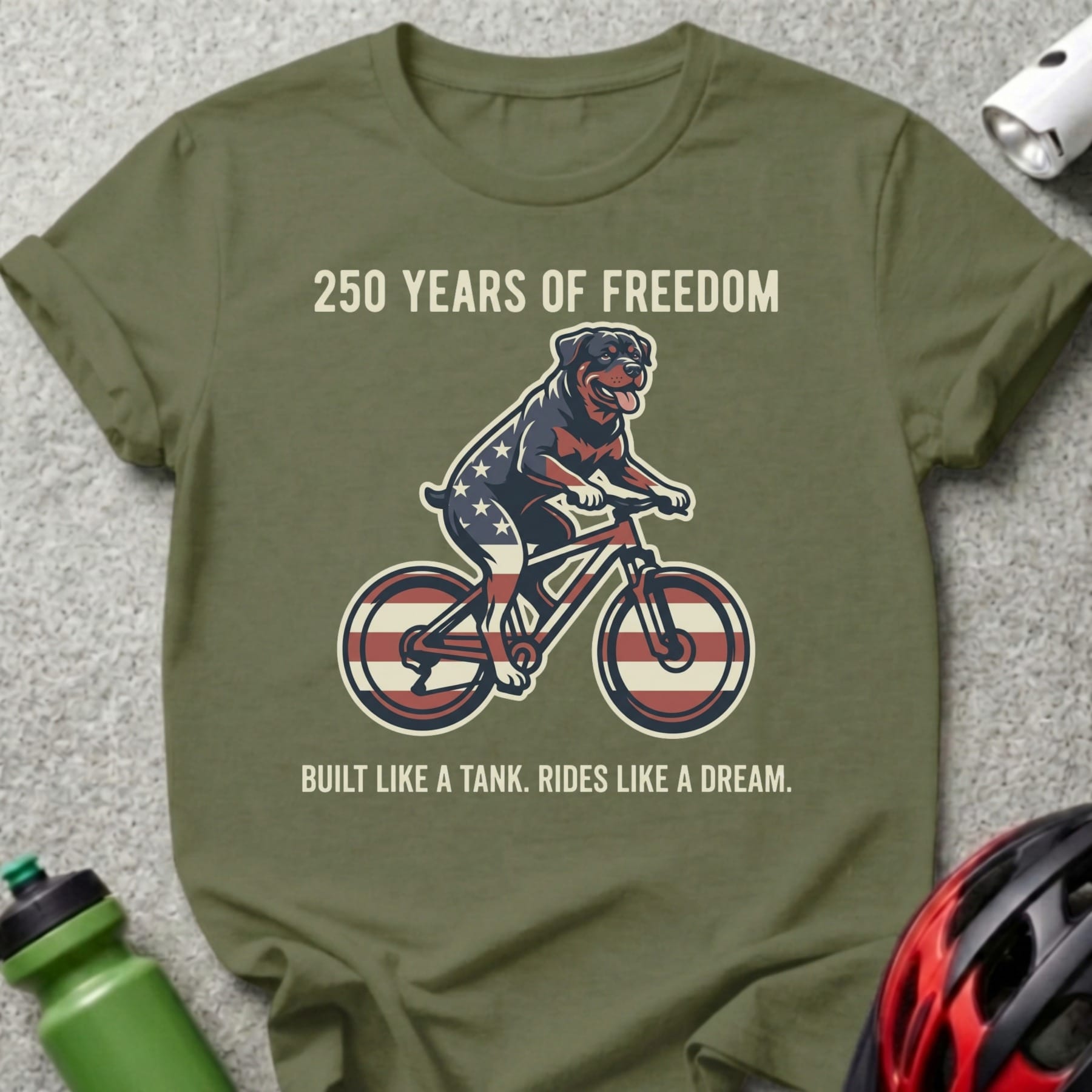 Olive green t-shirt with patriotic dog riding a bicycle graphic.
