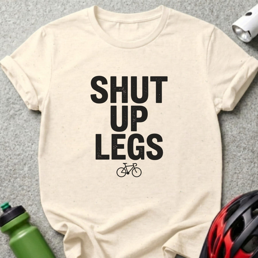 Cream t-shirt with black text "SHUT UP LEGS" and a bicycle icon.