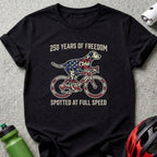 Black t-shirt with a dog in a flag pattern riding a bicycle.