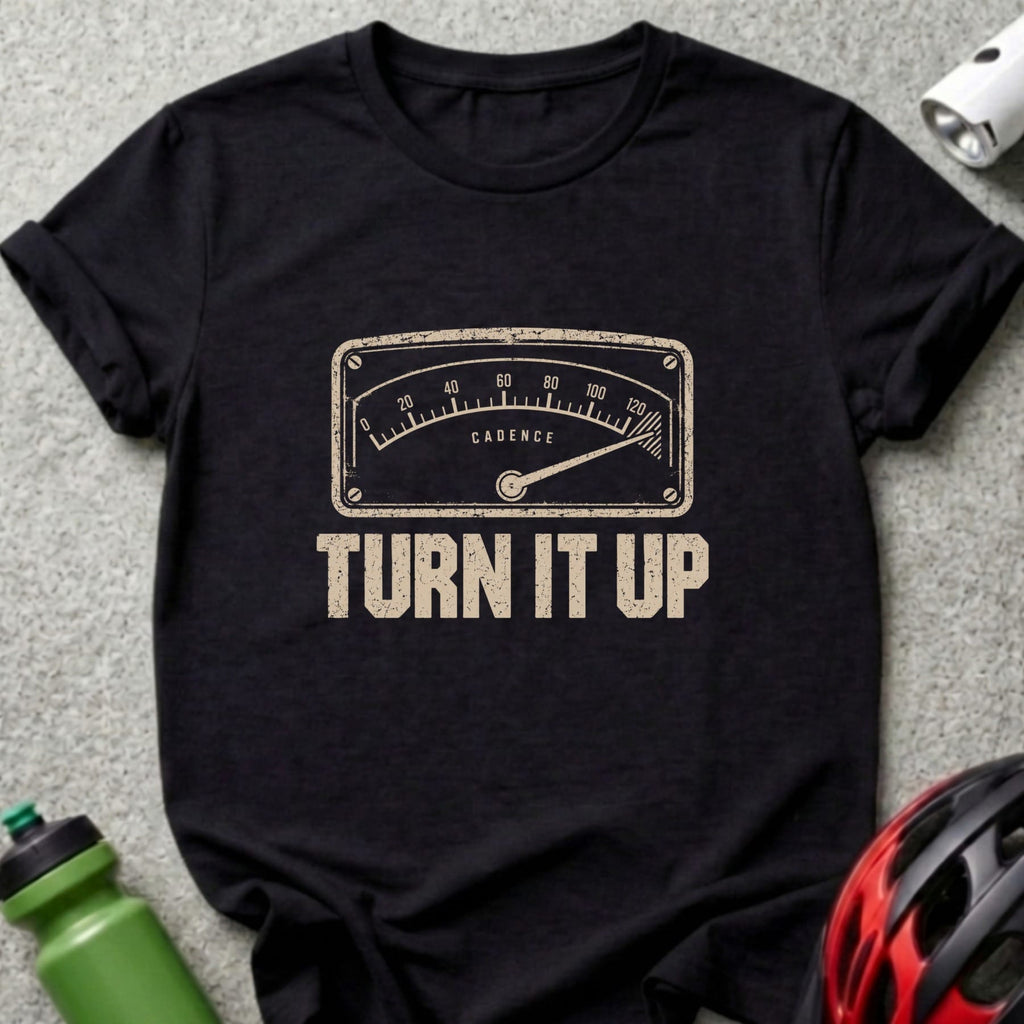 A black short-sleeved t-shirt featuring a beige cadence gauge graphic and the text TURN IT UP.