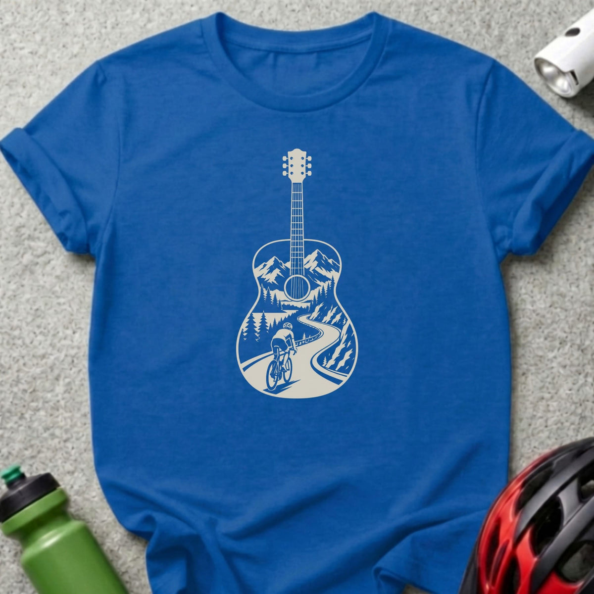 A blue crewneck t-shirt featuring a white graphic of an acoustic guitar containing a mountain cycling landscape.
