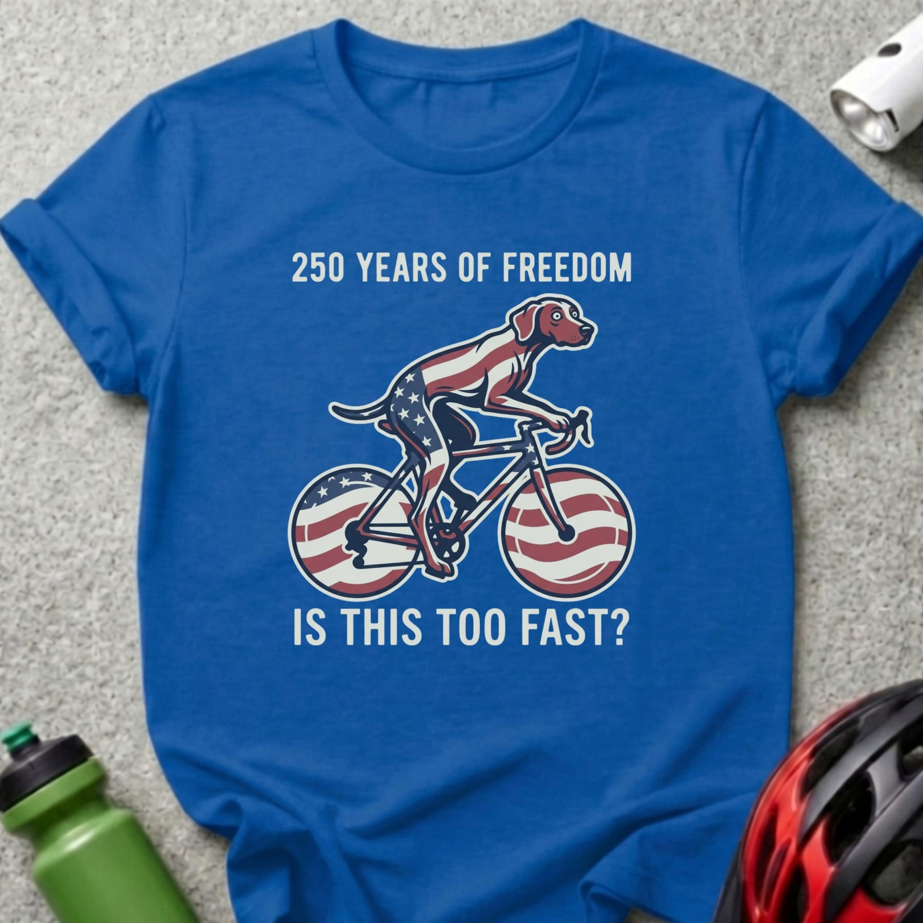 Blue t-shirt with dog riding a bicycle, celebrating 250 Years of Freedom.