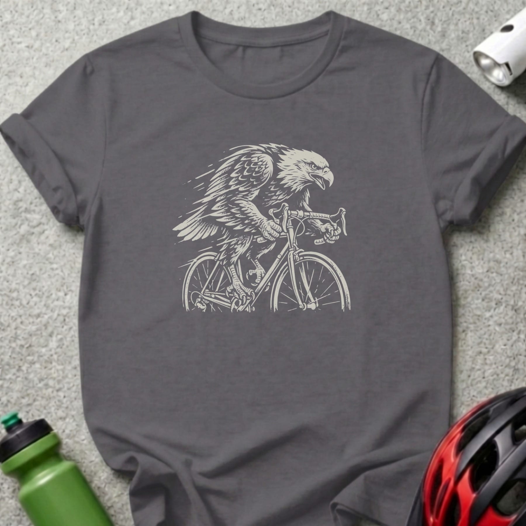 Eagle riding a bicycle, rendered in a sketch style on a dark grey t-shirt.