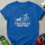 A blue t-shirt featuring a white graphic of a cyclist and dog with text saying "Every Ride Is A Group Ride."