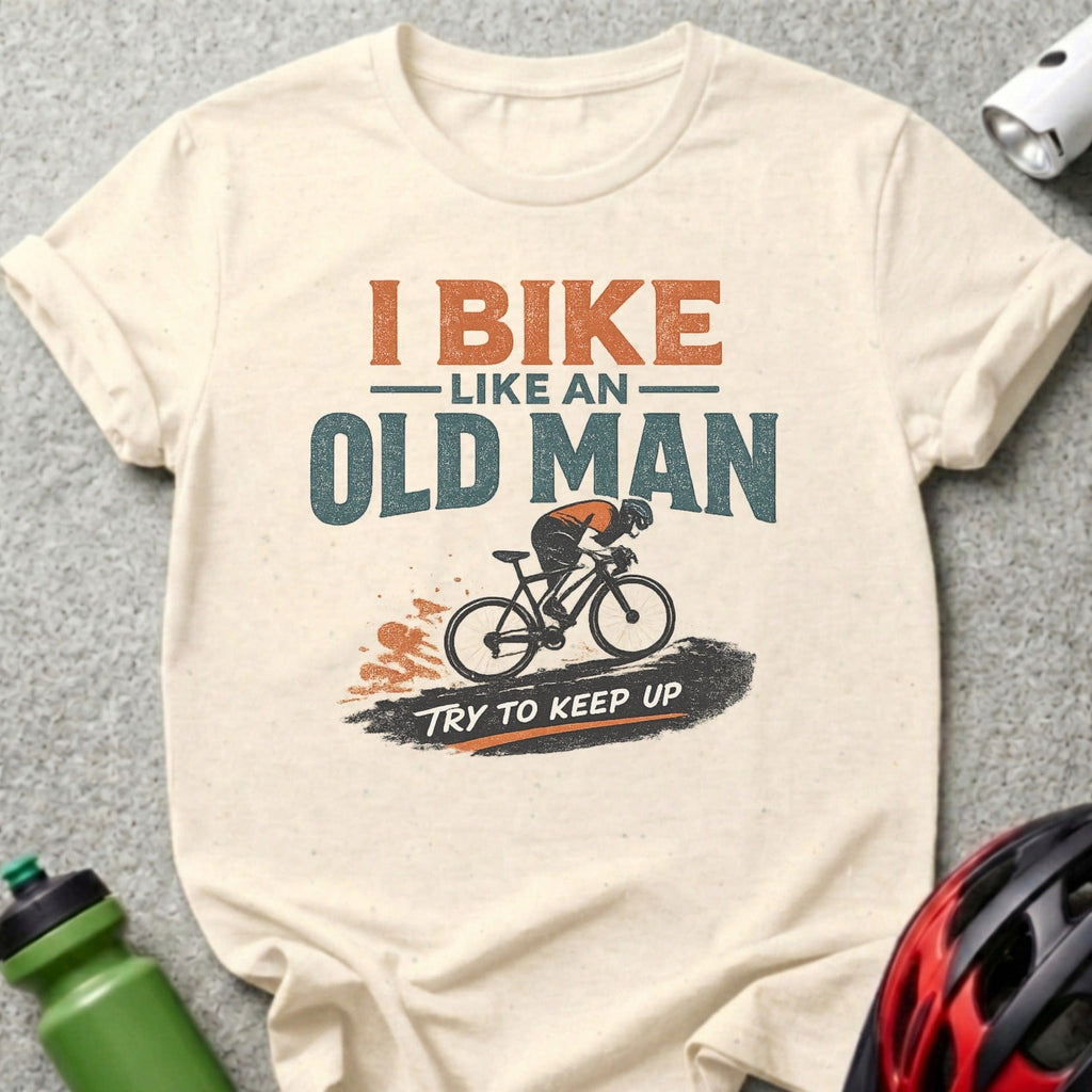 Cream t-shirt with graphic of a cyclist and text "I BIKE LIKE AN OLD MAN TRY TO KEEP UP".