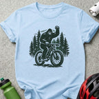 Bigfoot riding a bicycle through a forest, fist raised.