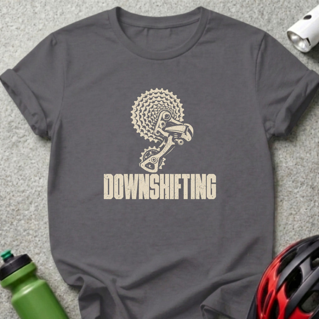 Charcoal gray t-shirt featuring a distressed beige graphic of bicycle gears and the text DOWNSHIFTING.