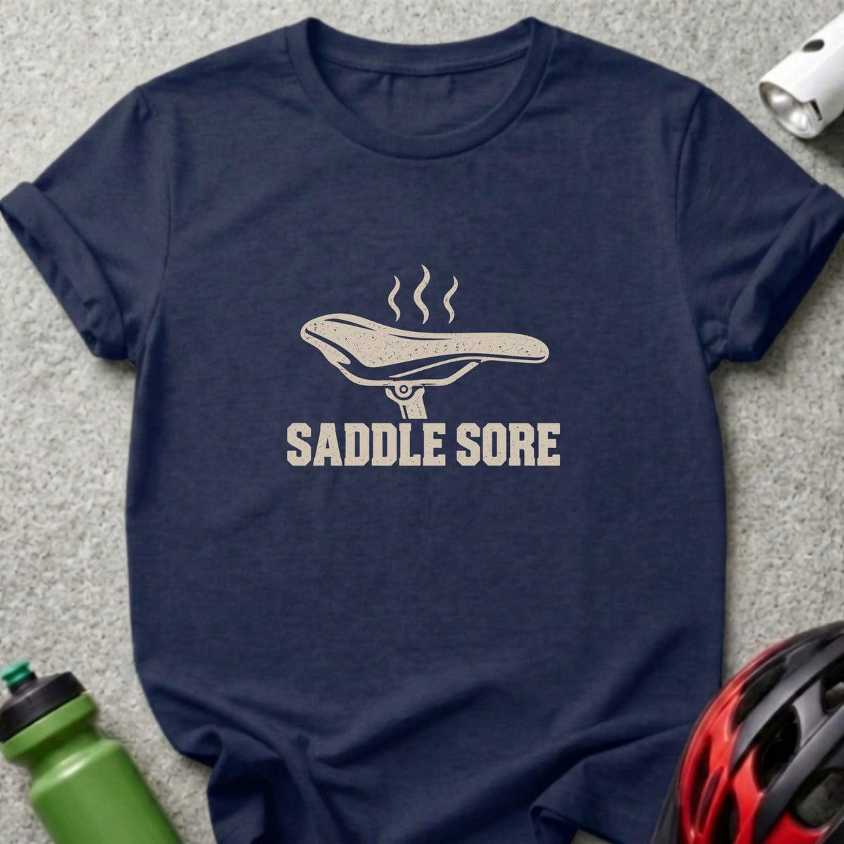 Dark blue t-shirt featuring a bicycle saddle graphic with steam and the text SADDLE SORE.