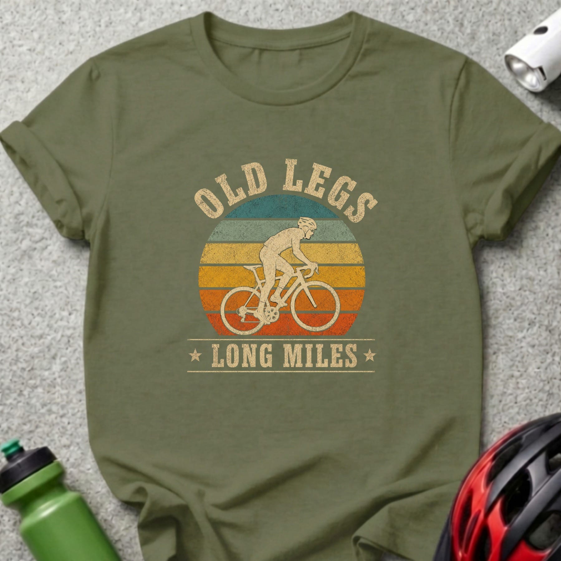 Olive green t-shirt with vintage cyclist graphic and text "OLD LEGS LONG MILES".