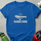 Royal blue crewneck t-shirt featuring a white graphic of a smoking bicycle saddle and the text SADDLE SORE.