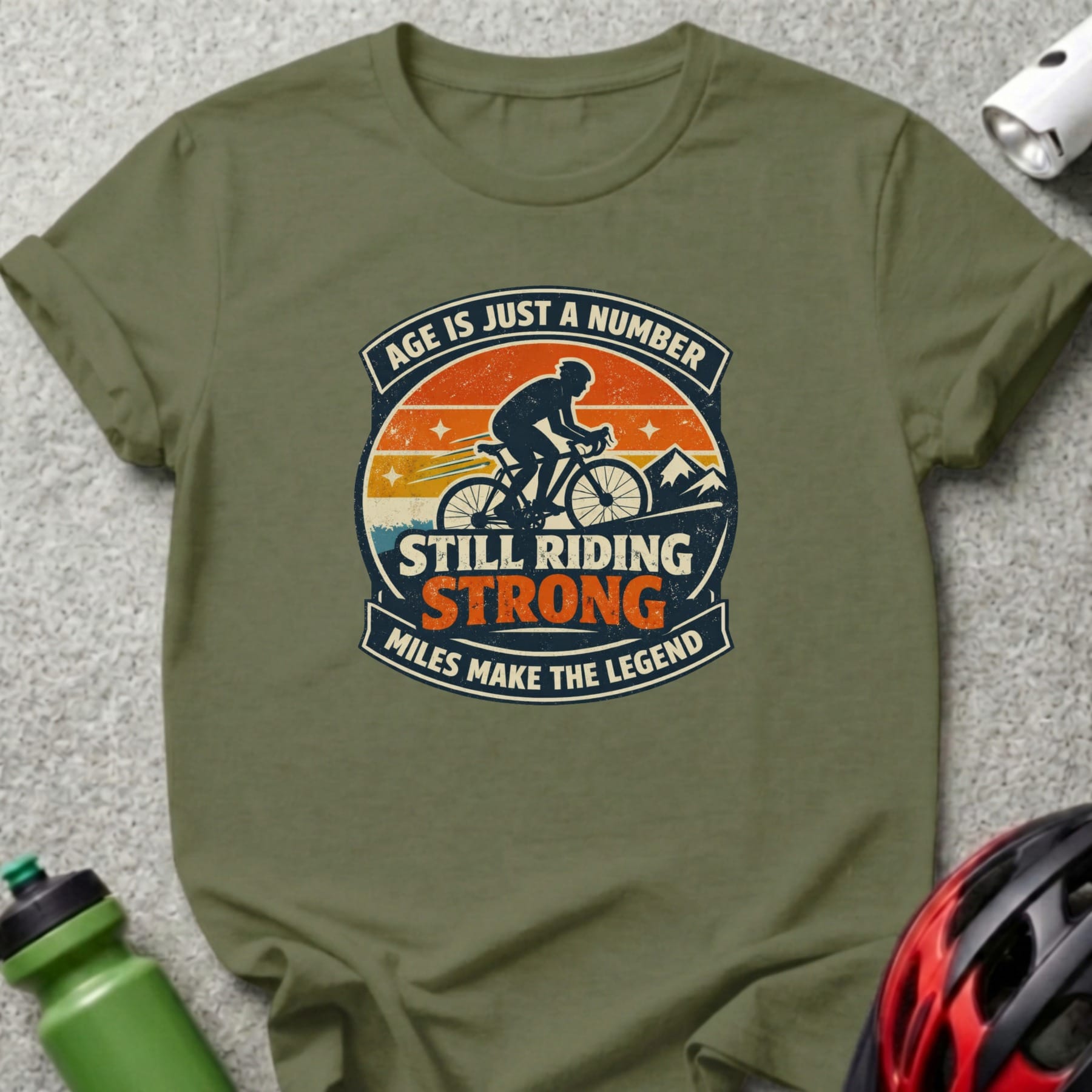 Olive green t-shirt with graphic "Age is just a number. Still riding strong. Miles make the legend."
