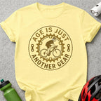 Yellow t-shirt with "Age is just another gear" cyclist graphic.